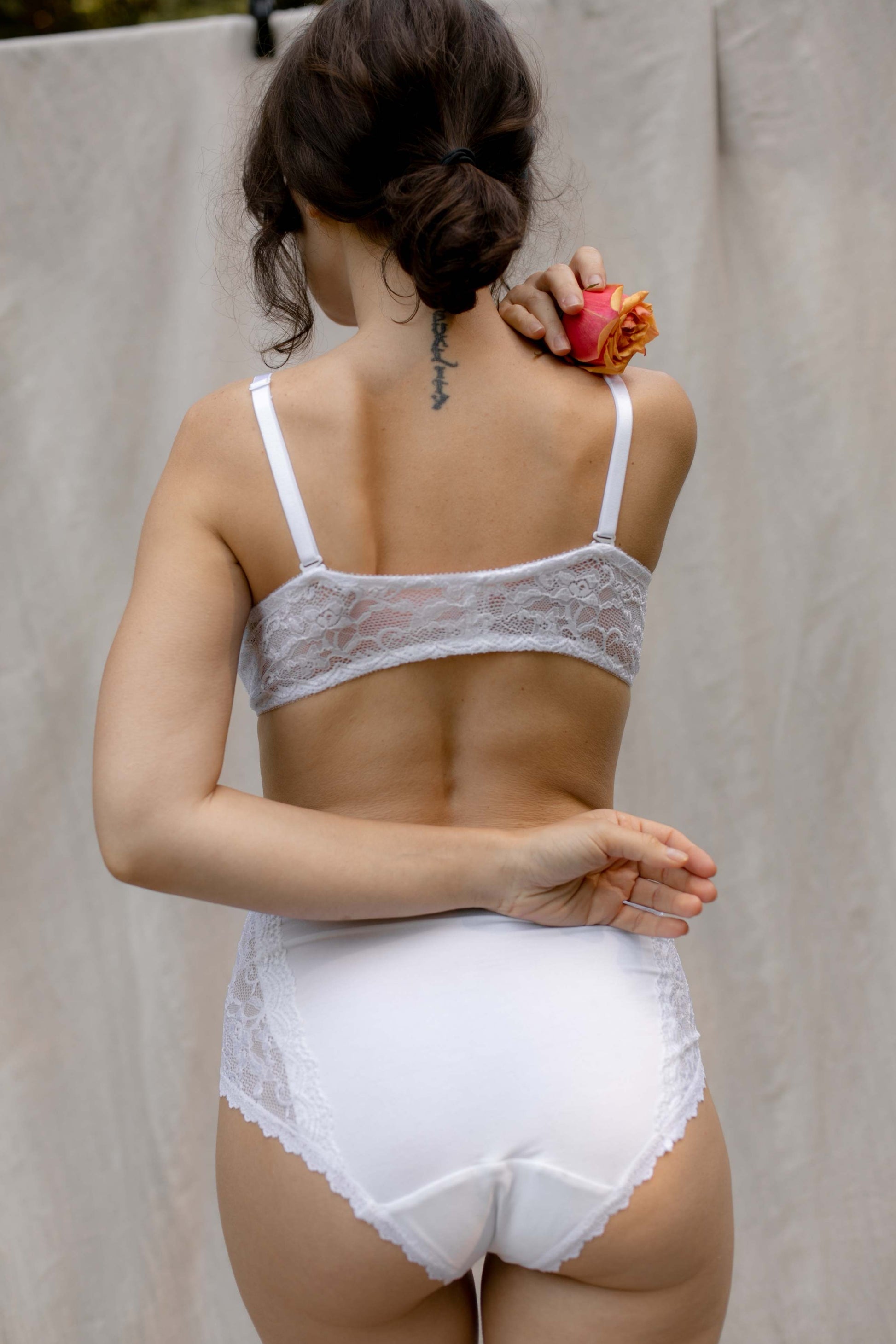 woman with turned back wearing white lace bra and white lace high waisted panty